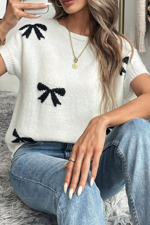 White knit tunic with black bow motif, crew neck, short sleeves.