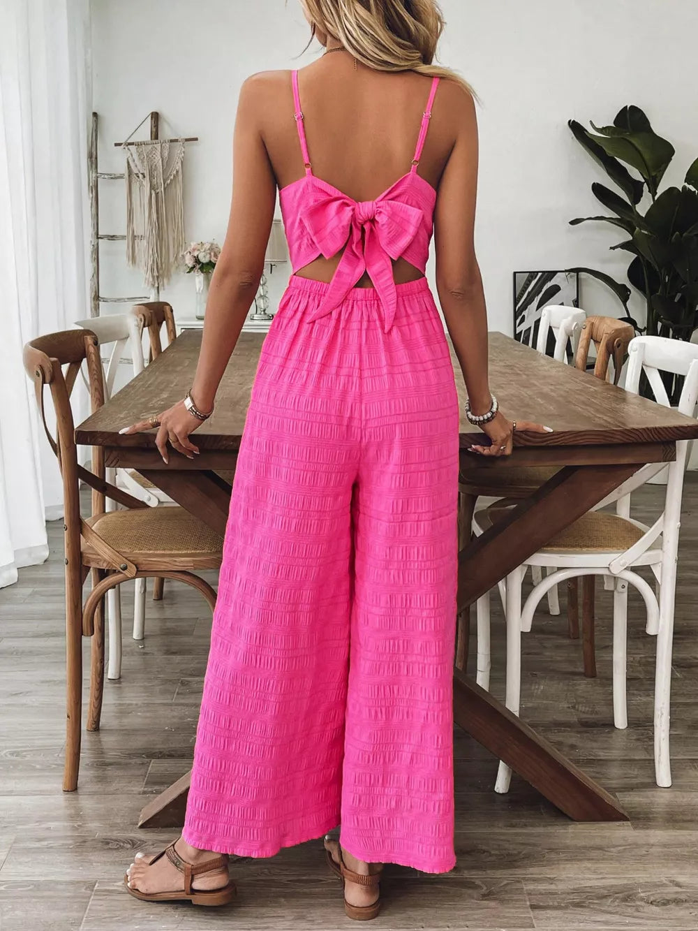 Rose red maternity romper with wide legs and a large back bow detail.