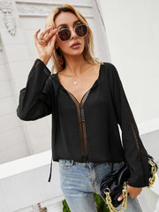 Black lace-inset blouse with slit sleeves and tie-neck detail.