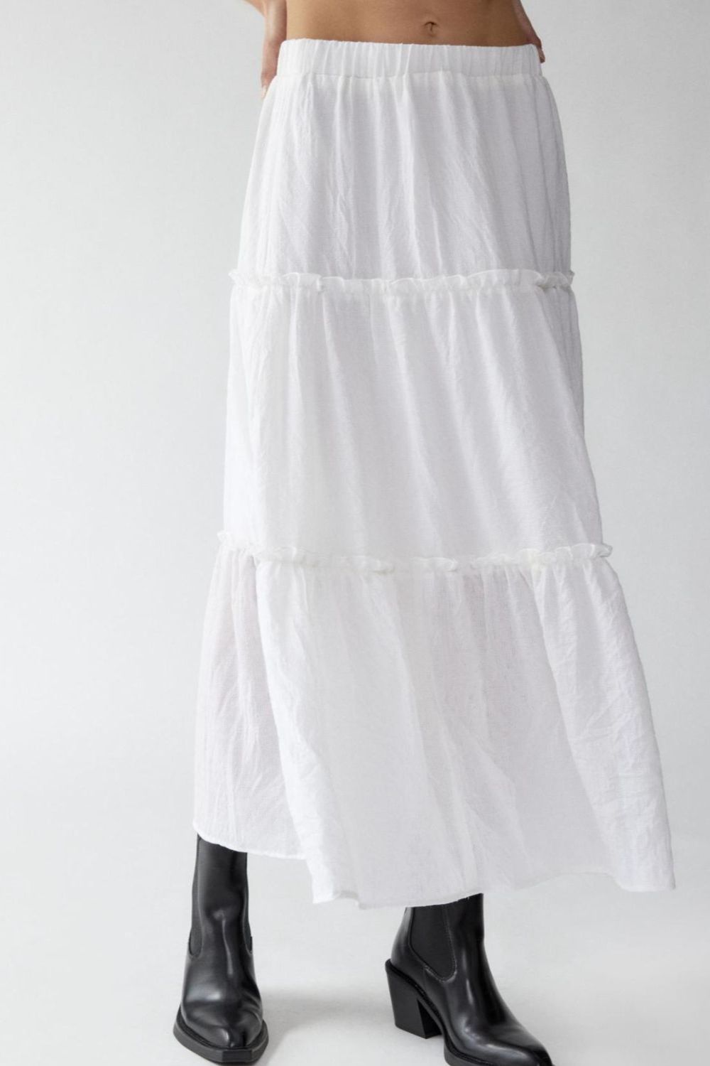 Tiered cotton maxi skirt in white with ruffled tiers, styled with black boots.