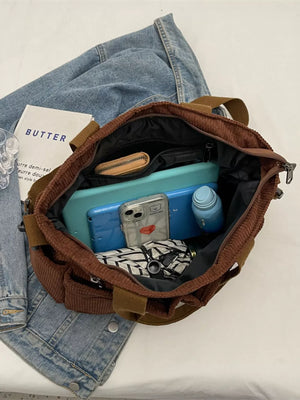 Brown corduroy crossbody bag with multiple pockets, showing contents like phone and wallet.