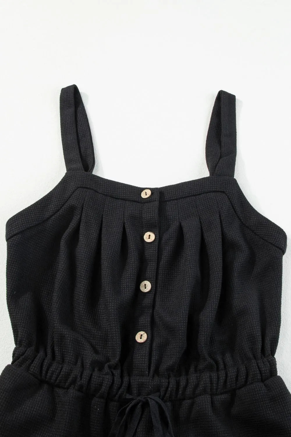 Black waffle knit jumpsuit with button front, drawstring waist and wide legs.