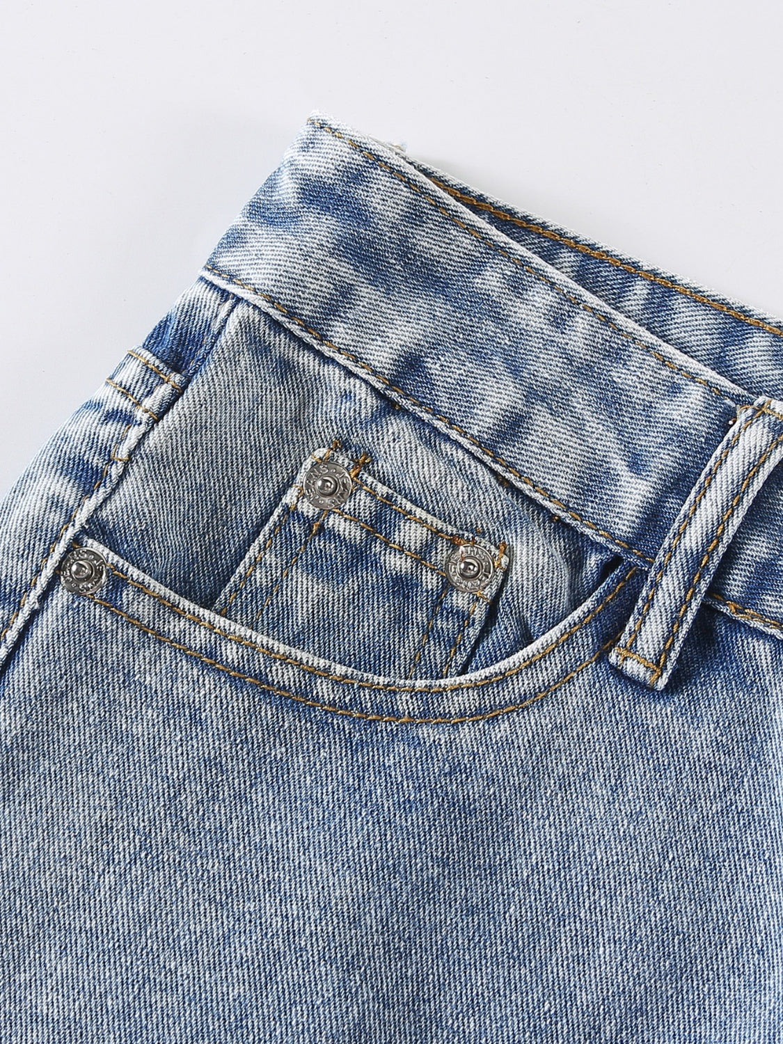 Light wash denim jeans with distressed details and shredded knee accents.