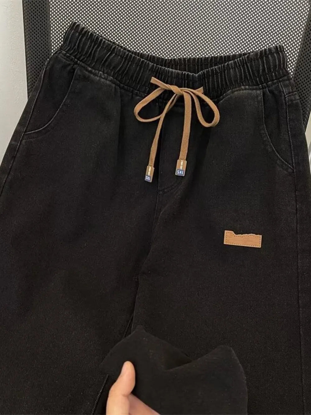 Black wide-leg jeans with drawstring waist and side pockets.