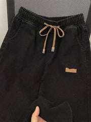 Black wide-leg jeans with drawstring waist and side pockets.