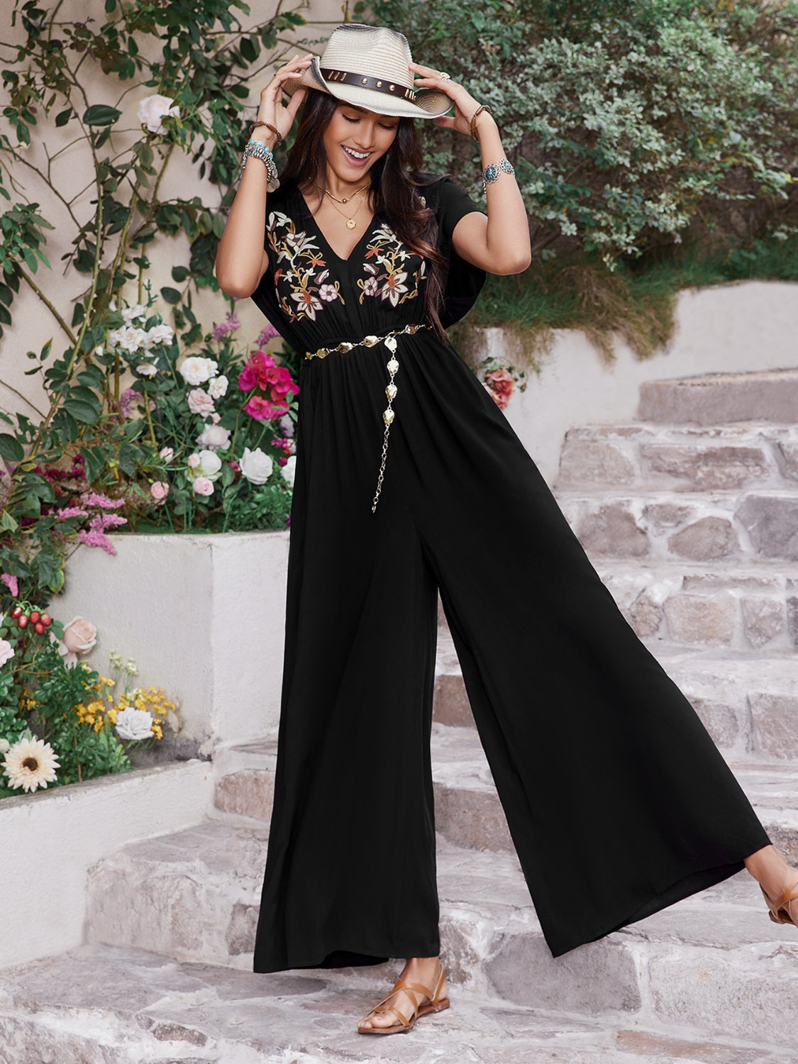 Black embroidered flutter sleeve wide-leg jumpsuit with a v-neck and chain belt.