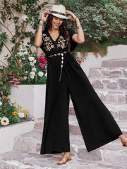 Black embroidered flutter sleeve wide-leg jumpsuit with a v-neck and chain belt.