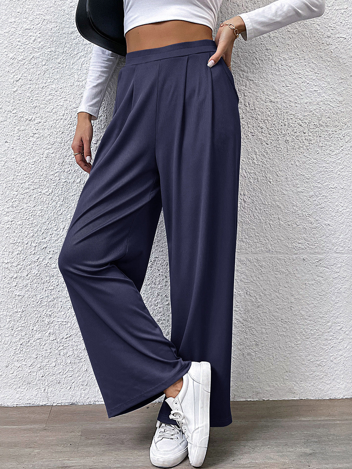 Navy pleated front wide leg trousers with a relaxed fit, styled casually.