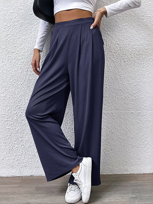 Navy pleated front wide leg trousers with a relaxed fit, styled casually.