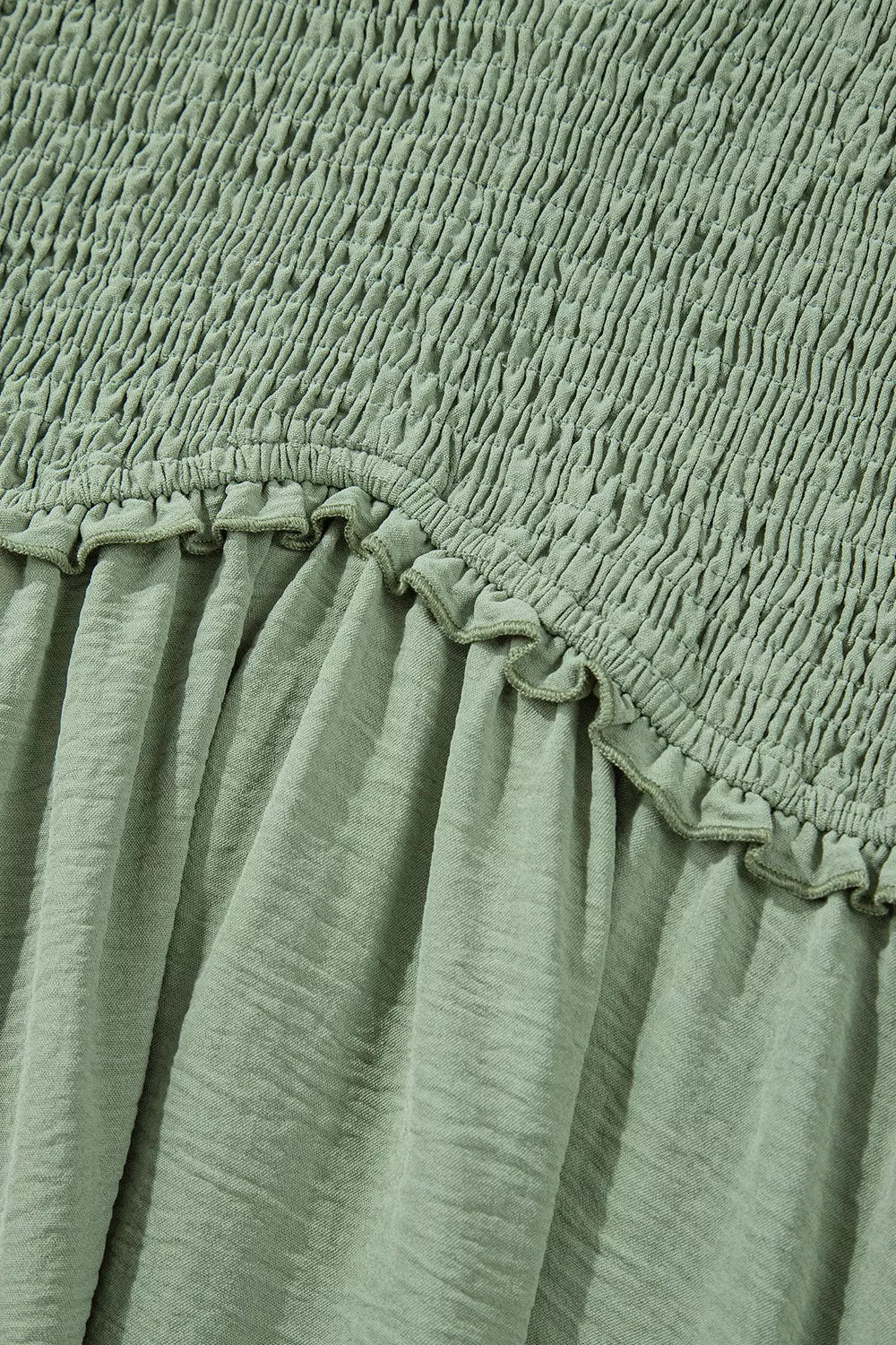 Sage smocked V-neck mini dress with frill detail and textured fabric.