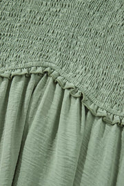 Sage smocked V-neck mini dress with frill detail and textured fabric.