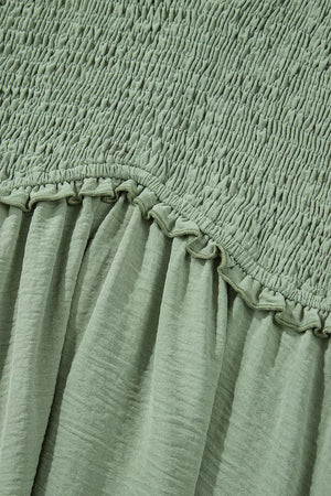 Sage smocked V-neck mini dress with frill detail and textured fabric.