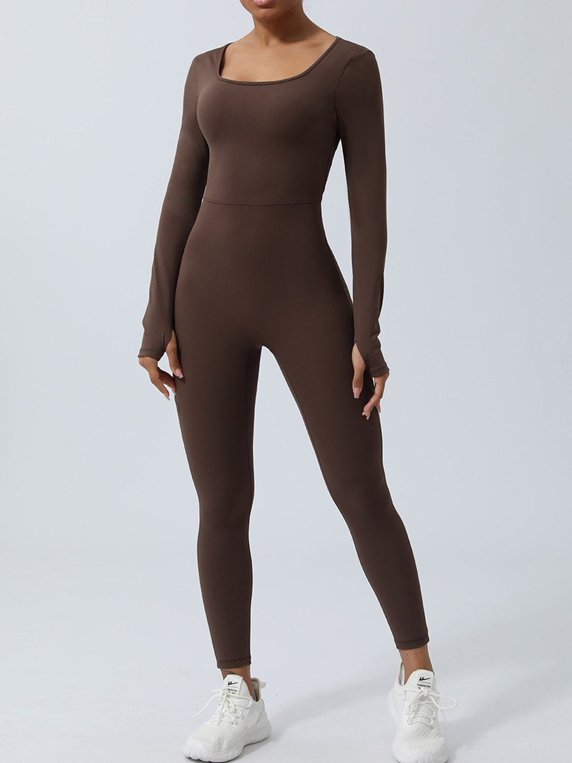 Chocolate long sleeve sculpting jumpsuit with square neckline and thumbholes, styled with white sneakers.