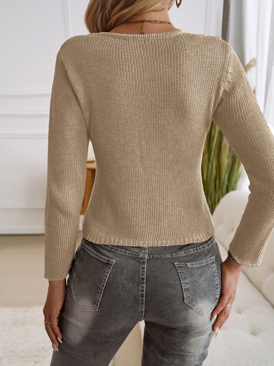 Tan knit cropped cardigan with long sleeves and a ribbed hem, shown from the back.