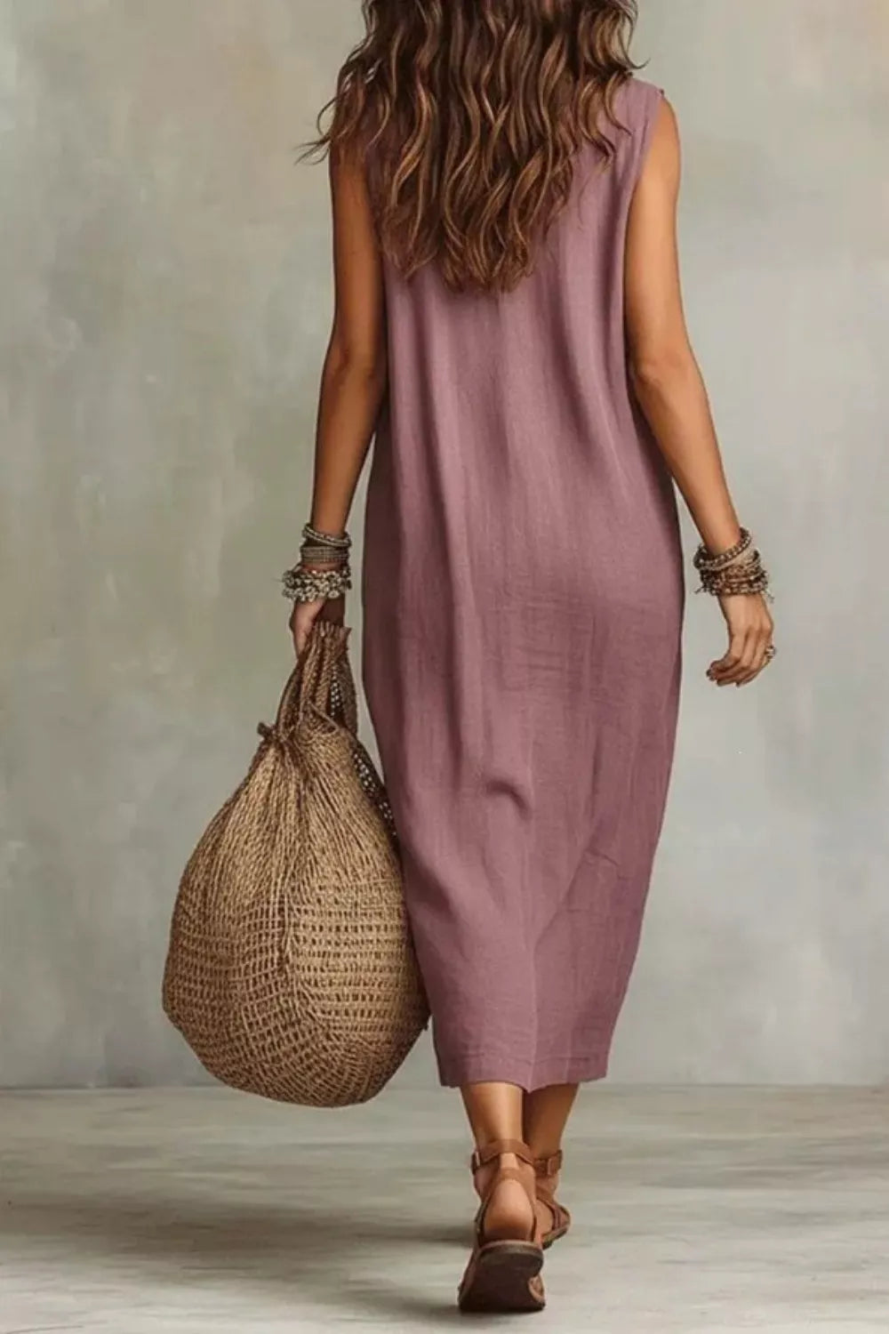 Dusty Pink midi dress with cowl neck, sleeveless, and pockets, worn with sandals and a woven bag.