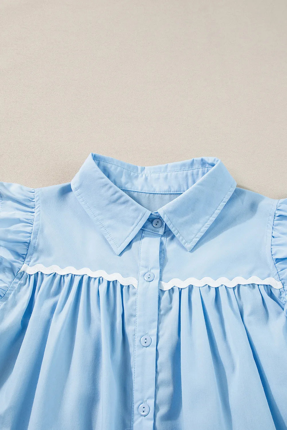 Light blue poplin blouse with ruffled yoke and white scalloped trim detail.