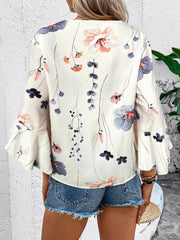 White floral bell sleeve blouse with ruffled cuffs.