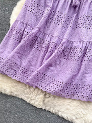 Purple eyelet tiered maxi skirt with cutout details and tassel drawstring.