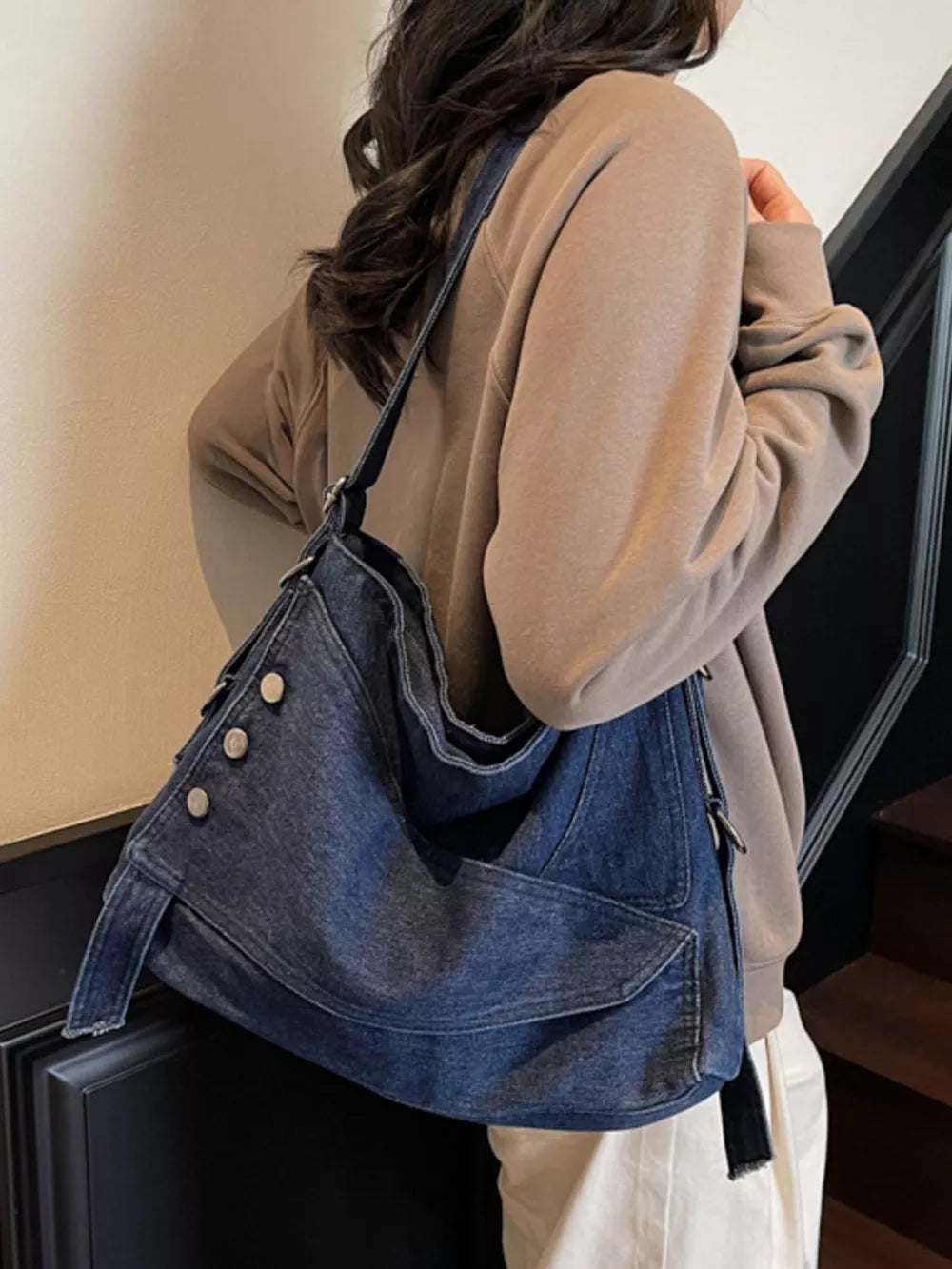 Relaxed denim crossbody bag with button accents and adjustable strap.