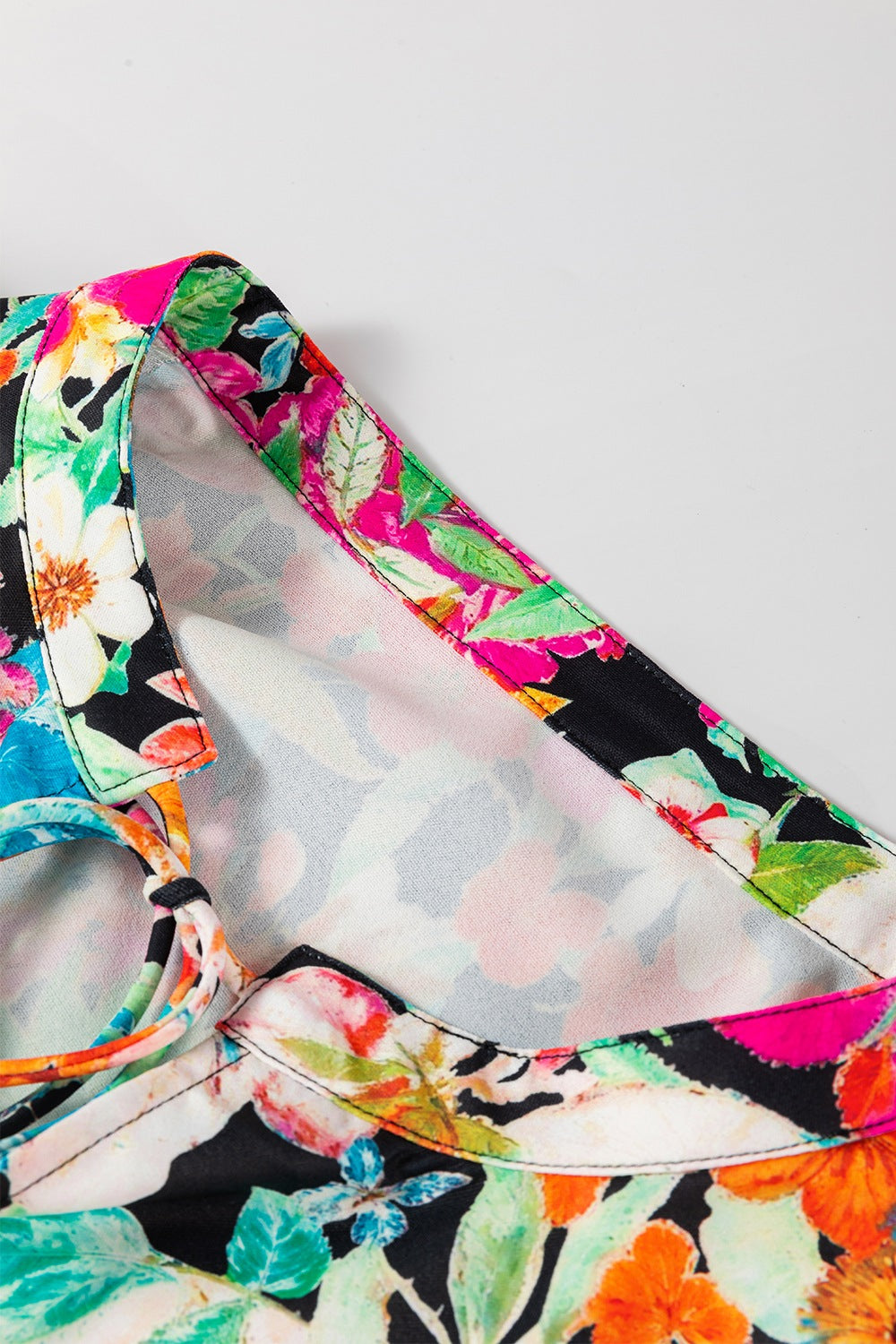 Vibrant floral print blouse with tie detail and colorful trim.