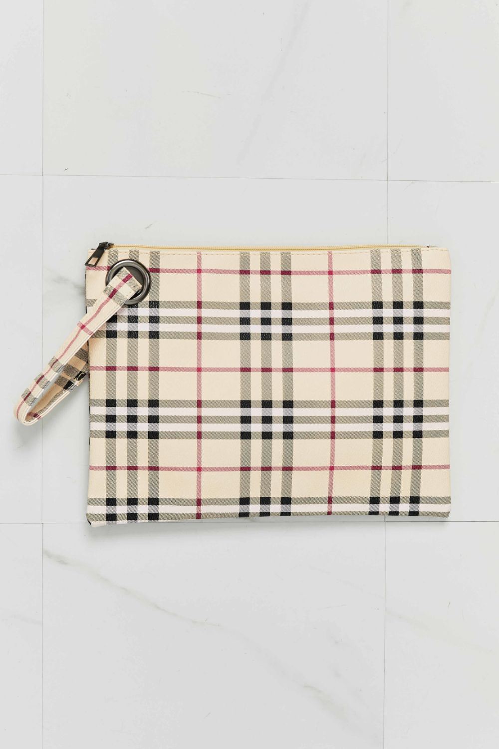 Plaid wristlet clutch bag in cream with black, red, and white lines, featuring a grommet detail and wrist strap.