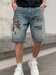 Men's denim shorts with graphic patchwork details and a distressed wash.