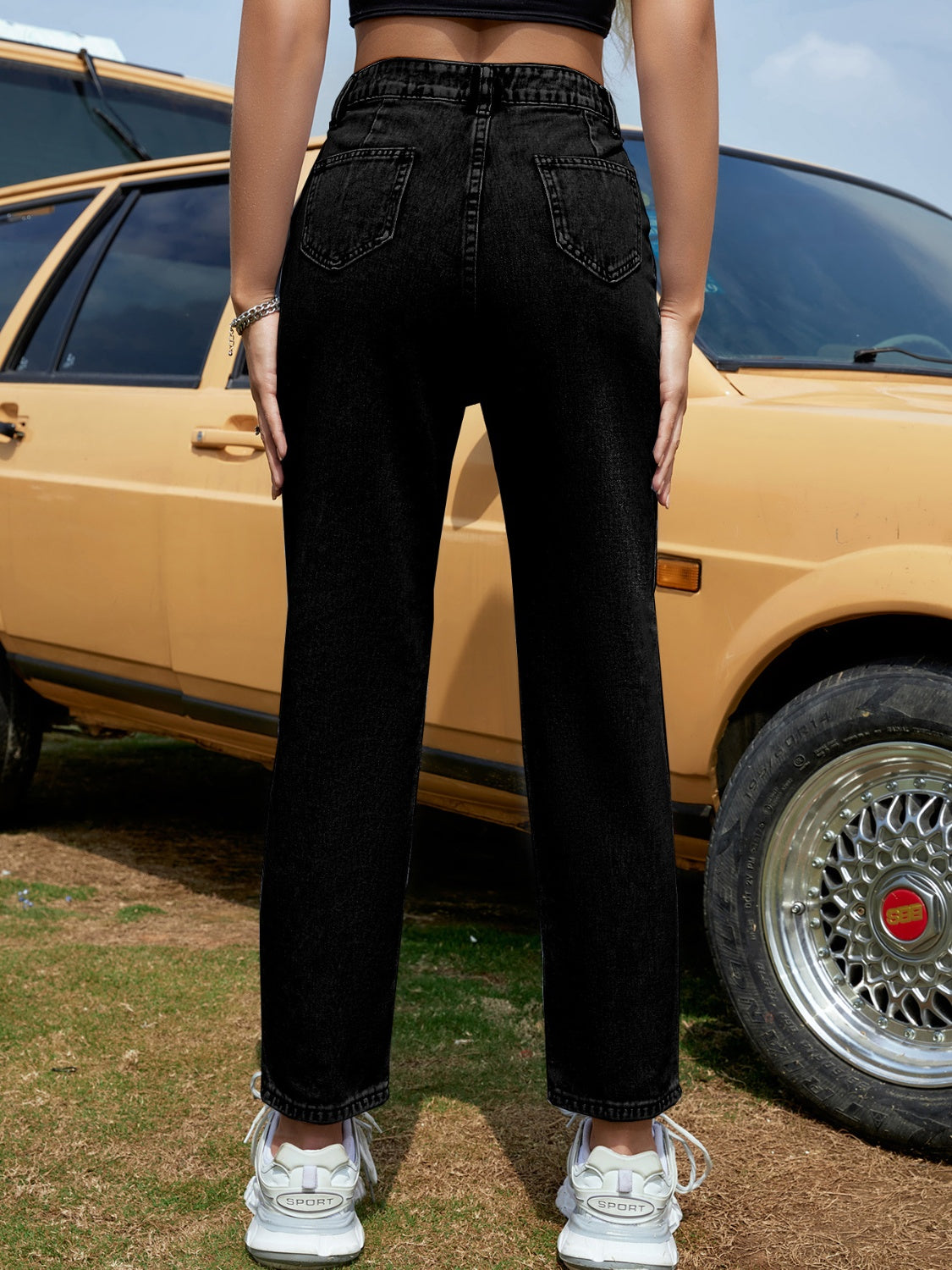 Black high-waisted tapered denim trousers with buttoned closure and casual chic style.