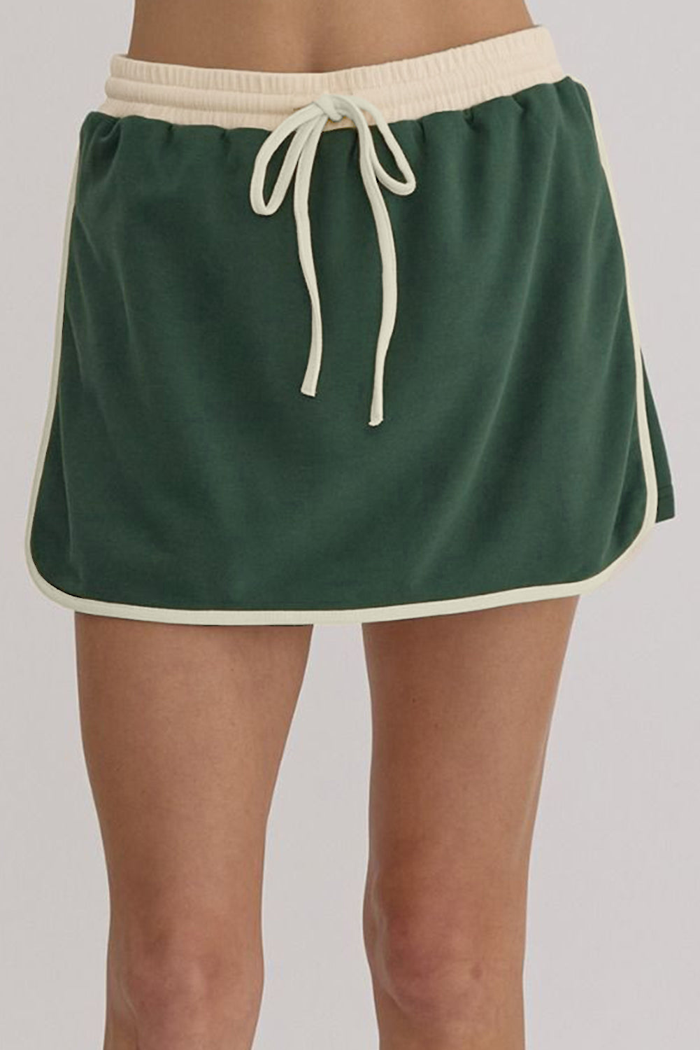 Dark green skort with cream trim and drawstring waist, part of a set.