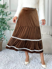 Brown velvet midi skirt with tiered ruffles and wavy white trim detail.