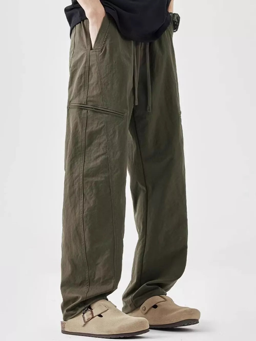 Olive green men's wide-leg sweatpants with drawstring and zip pocket detail.