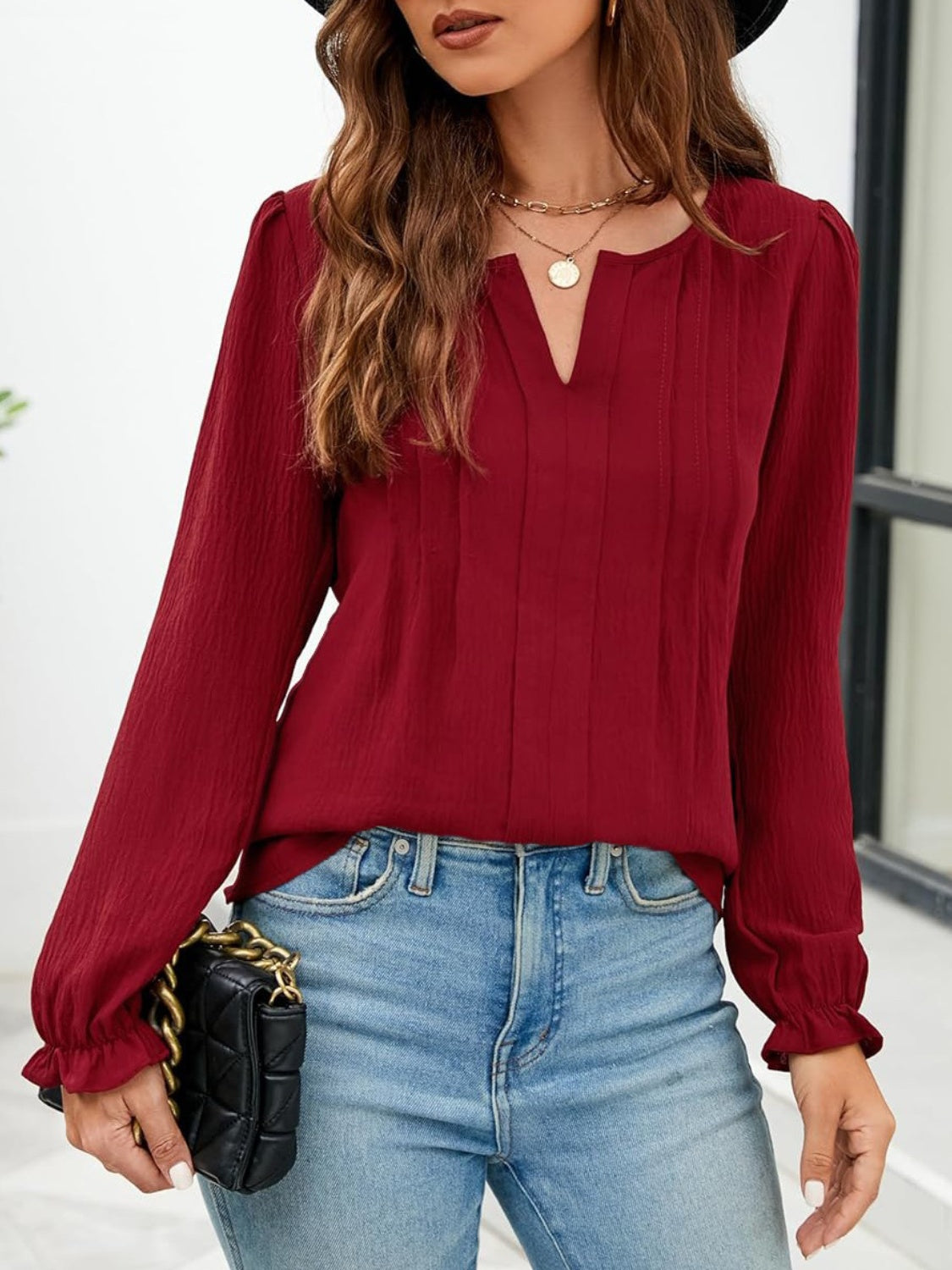 Burgundy textured blouse with pleats and ruffle cuffs, V-neck, long sleeves.