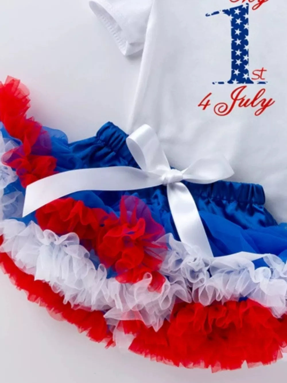 Baby outfit with white top saying 1st 4 July and red, white, blue ruffled tutu skirt.