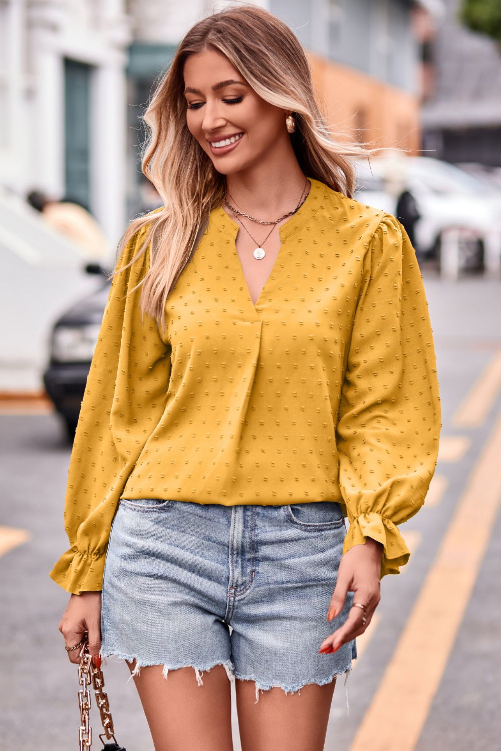 Gold textured dot v-neck blouse with ruffle cuffs and long sleeves.