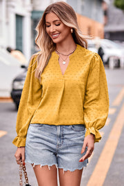 Gold textured dot v-neck blouse with ruffle cuffs and long sleeves.
