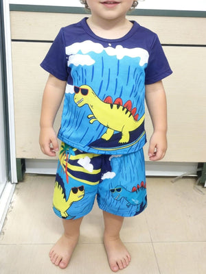Toddler blue dinosaur graphic tee and shorts set with sunglasses and palm trees.