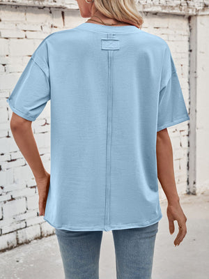 Light blue cotton oversized tee with seam detail and rolled sleeves.