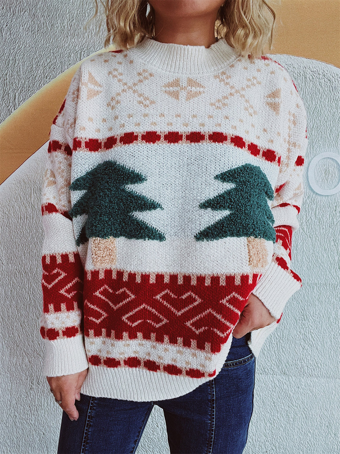 Beige knit sweater with festive appliqué Christmas trees, snowflakes, and geometric patterns.