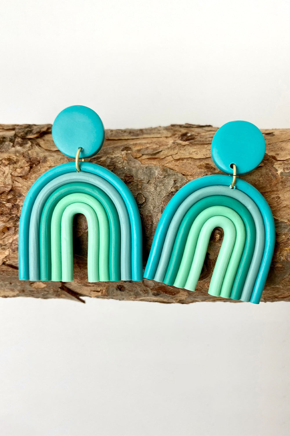 Aqua rainbow arch clay earrings with multiple shades of blue and green.