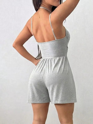 Light gray ruched spaghetti strap romper with a cinched waist and short shorts.