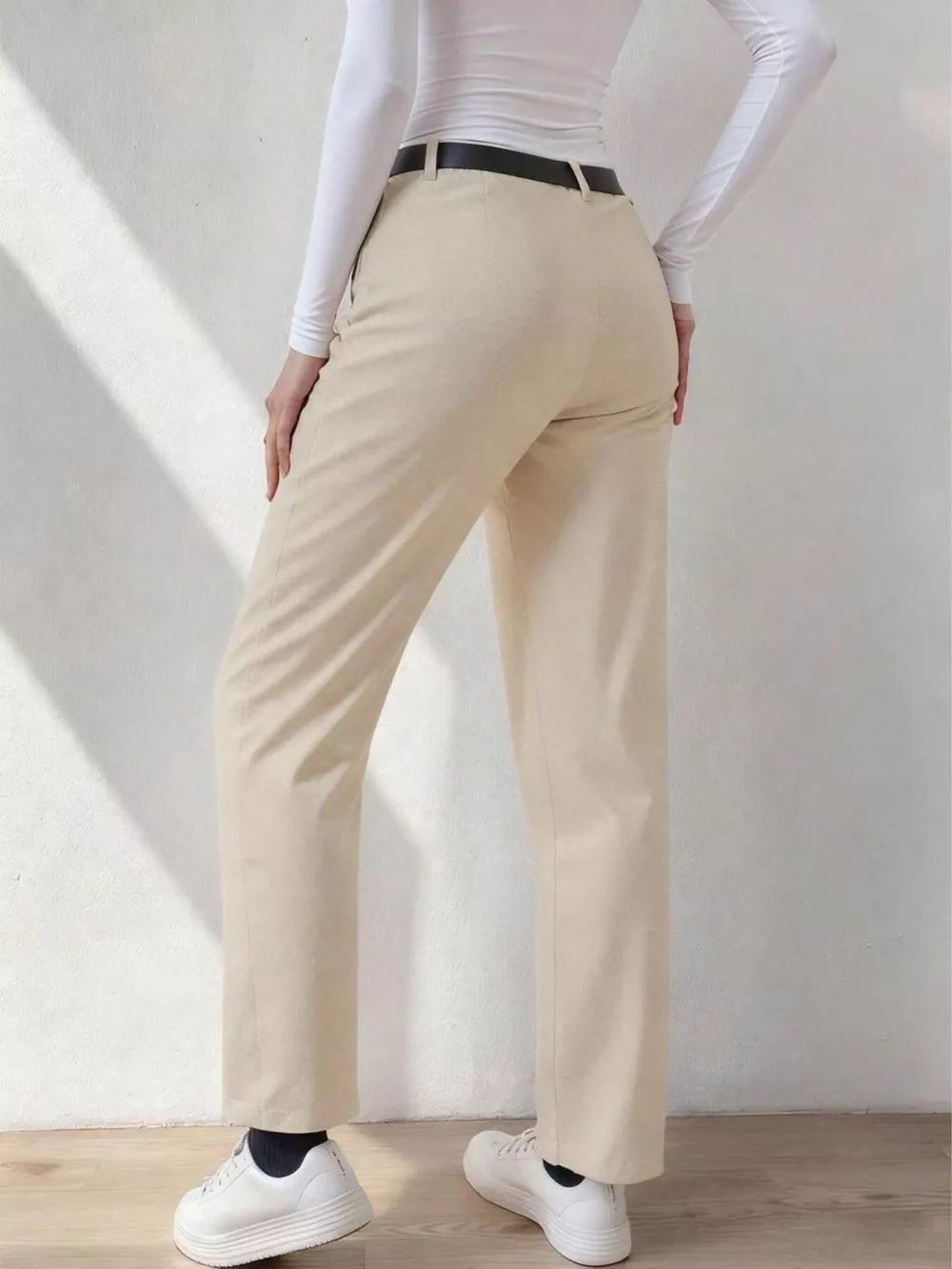 Beige wide-leg dress pants with pockets and belt loops, styled with a white top and black belt.