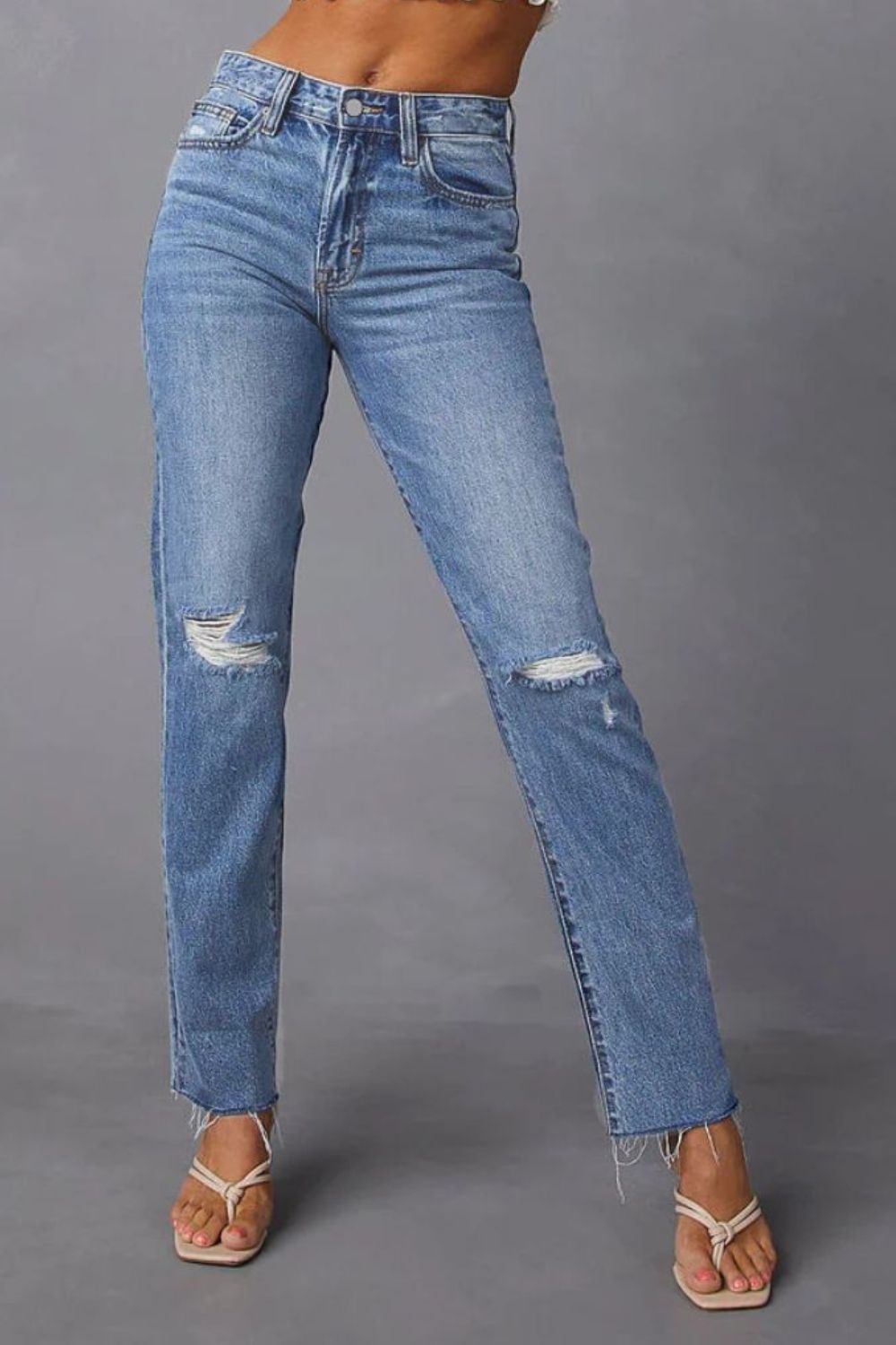 Distressed straight leg jeans in medium wash denim with ripped knees and frayed hem.