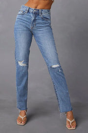 Distressed straight leg jeans in medium wash denim with ripped knees and frayed hem.