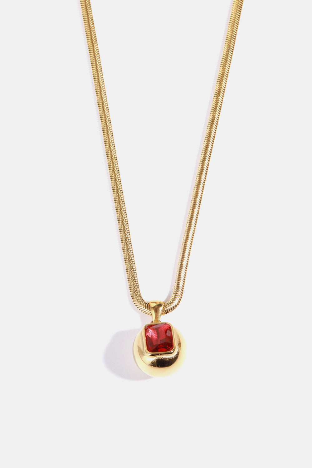 Gold necklace with orb pendant and deep red square stone