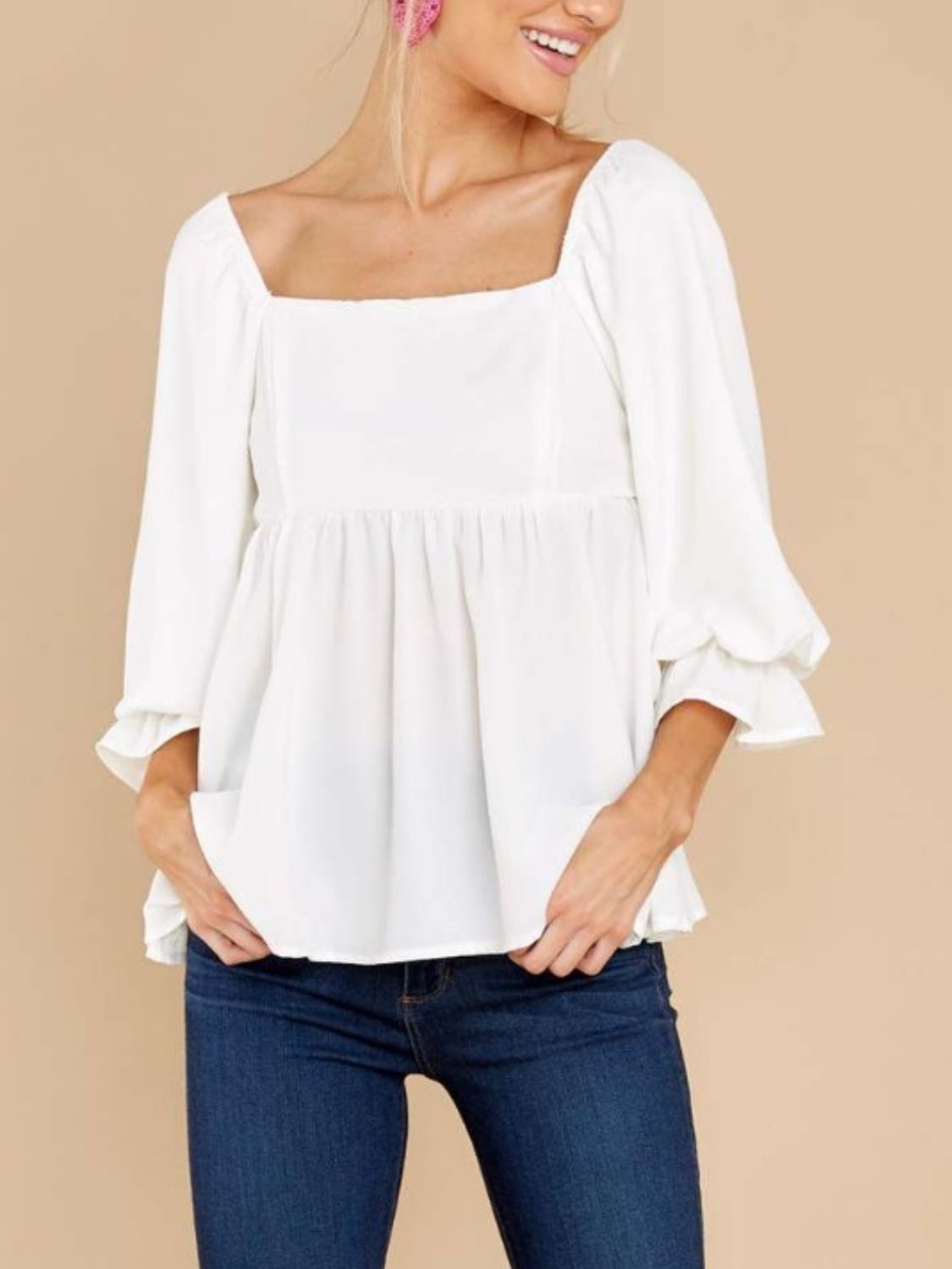 White babydoll blouse with square neckline, smocked back detail, and ruffled cuffs.
