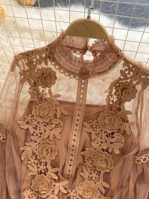 Light brown lace blouse with floral embroidery and ruffled mock neck, paired with cami.