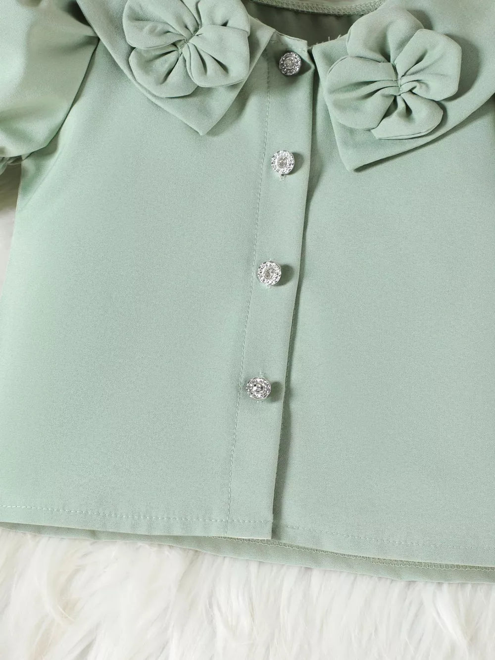 Green toddler top with ruffled collar, bow details, and crystal buttons.