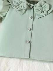 Green toddler top with ruffled collar, bow details, and crystal buttons.