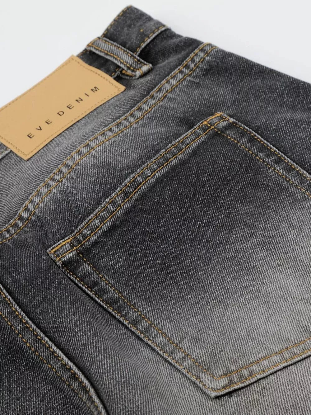 Men's black distressed wide-leg cotton jeans with tan leather back patch.