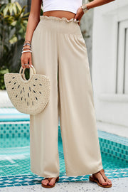 Tan smocked waist palazzo trousers with wide legs and a ruffled hem.