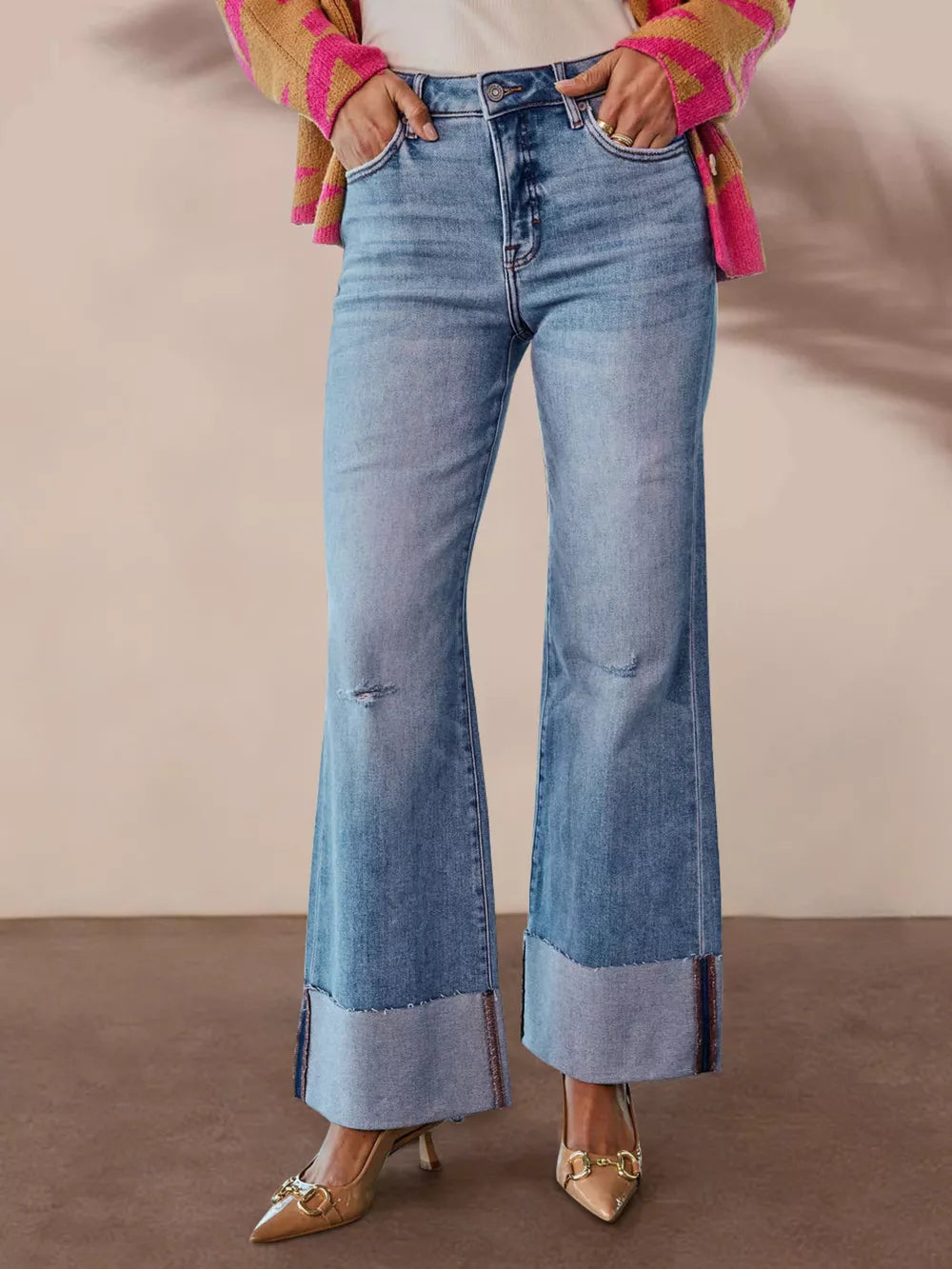 Distressed high-waisted flare jeans with raw hem and cuffed ankles in light wash denim.